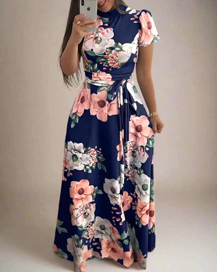 Woman wearing a floral dress taking a mirror selfie indoors.