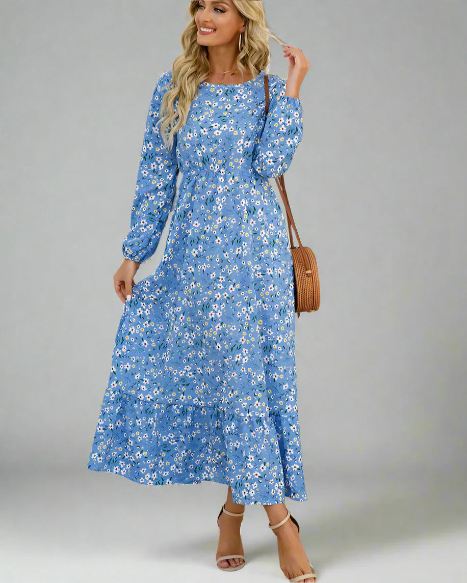 Woman wearing a blue floral dress with a white wall and plant in the background