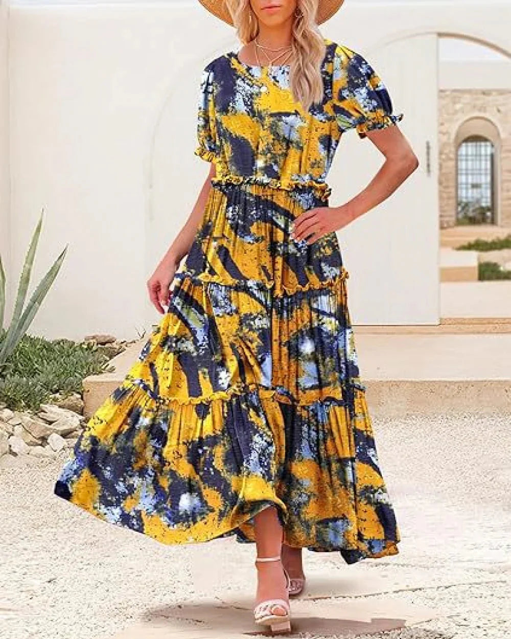 Woman wearing a yellow and blue floral dress standing outdoors.