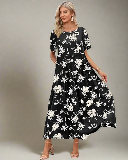 Woman in a black floral dress standing on a wooden deck with palm trees and ocean in the background