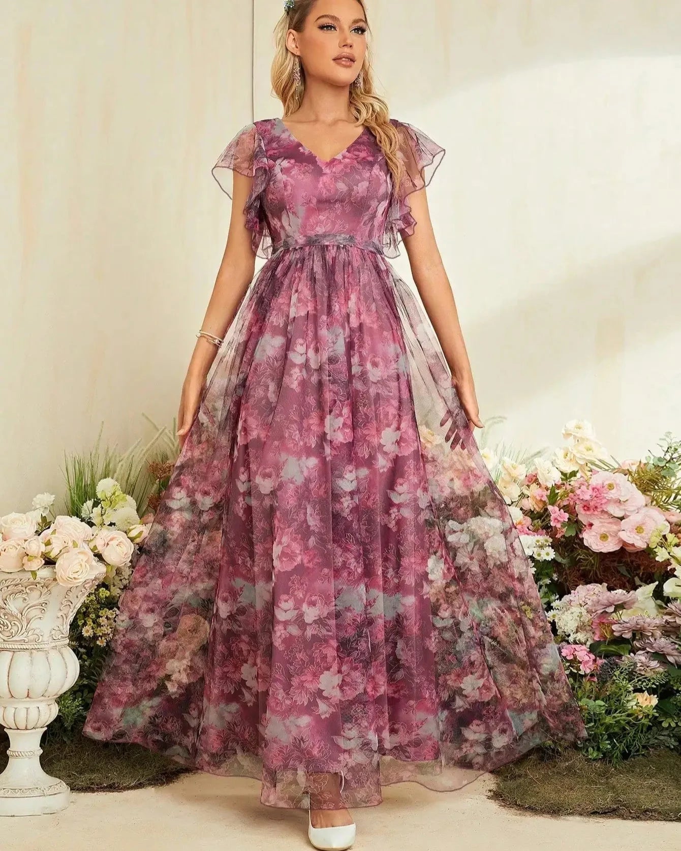Woman in a floral dress standing among flowers with a decorative background