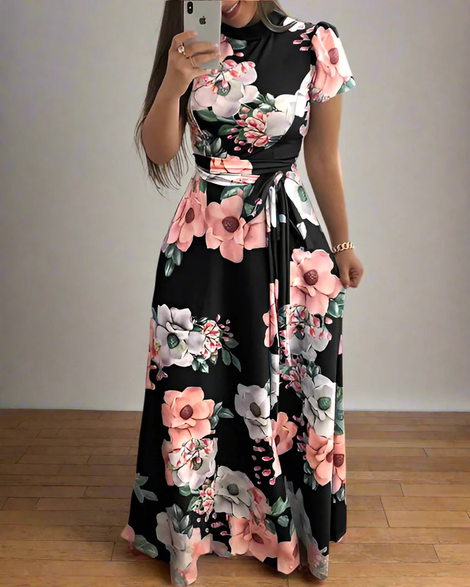 Woman wearing a black floral dress taking a mirror selfie indoors.