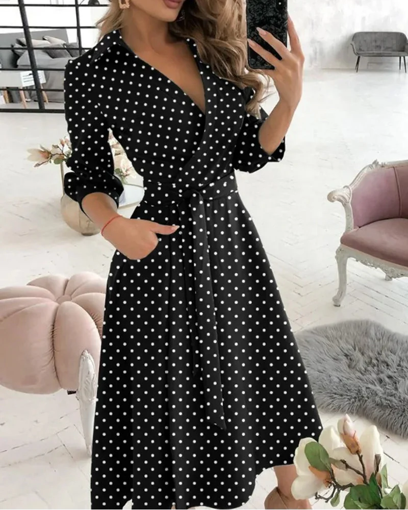 Woman wearing a black polka dot dress in a room with decor elements.
