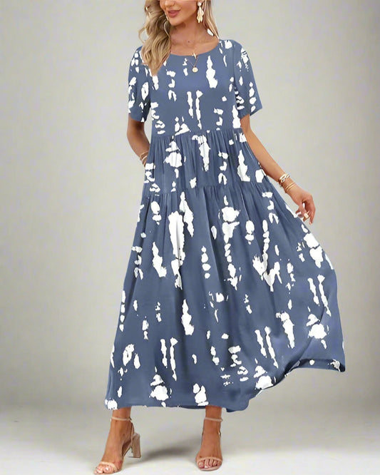 Woman wearing a blue and white patterned dress by a tropical beach.