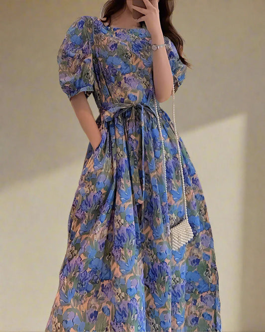 Woman wearing a blue floral dress taking a mirror selfie.